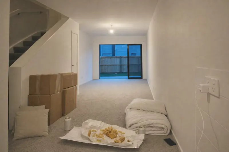 First night in a first home: fish and chips open on the lounge floor beside unopened boxes and a folded duvet