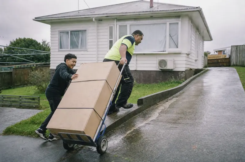 A personal loan at work: father and son wheel a new washing machine up a driveway in Ōtara, Auckland